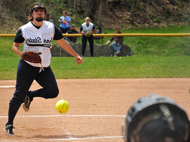 A softball leaving the hand of the pitcher and on route to the catcher